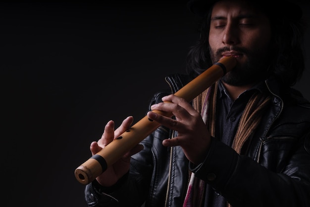 Foto fotografía de un joven músico peruano con charango y fondo negro por yuri ugarte