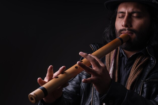 Foto fotografía de un joven músico peruano con charango y fondo negro por yuri ugarte