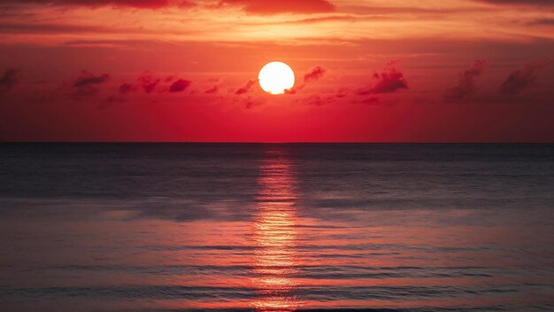 Fotografía a larga distancia del mar reflejando el sol con el cielo rojo