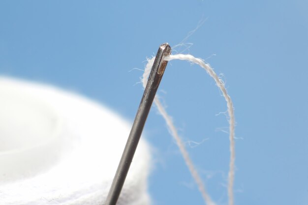 Fotografía macro de una aguja e hilo blanco