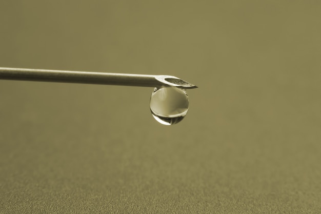 Fotografía macro de una aguja médica para inyección con una gota de líquido