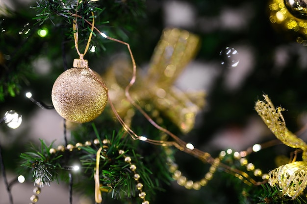 Fotografía macro de bola de oro y guirnalda de luz en el árbol de Navidad