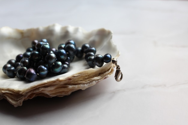 Fotografía macro de cuentas de perlas negras con piedras preciosas en una concha