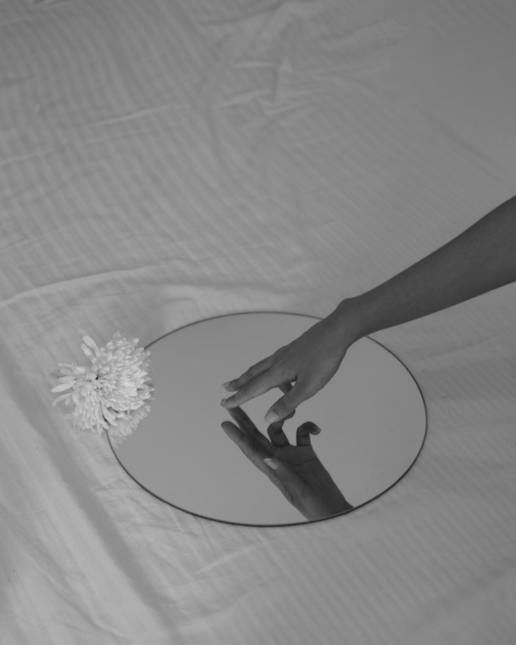 Foto fotografia monocromática de uma mão feminina em um espelho redondo colocado em uma cama