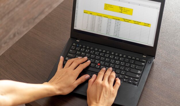 Fotografía de una mujer trabajando en la computadora portátil que muestra una hoja de Excel en la pantalla con la tabla de amortización de préstamos bancarios Contabilidad
