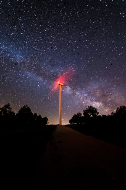 Fotografía nocturna de larga exposición con la Vía Láctea y su centro galáctico en un molino de energía eólica