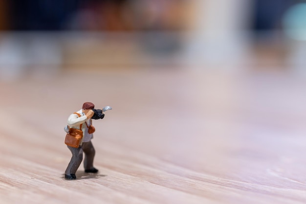 Fotografía de personas en miniatura sosteniendo una cámara y copiando espacio para texto