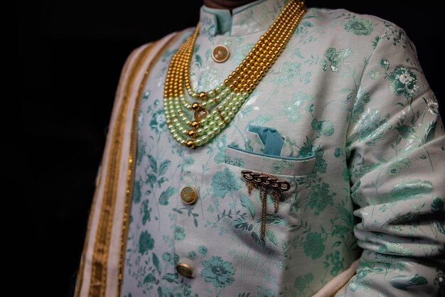 Foto fotografía en primer plano de un elegante traje de novio sherwani con un collar aislado sobre un fondo negro