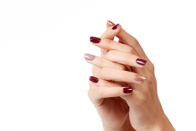 Fotografía en primer plano de las manos de una mujer con esmalte de uñas colorido sobre un fondo blanco