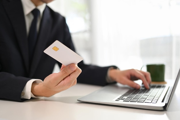 Fotografia recortada de um empresário fazendo uma compra ou pagamento com cartão de crédito on-line