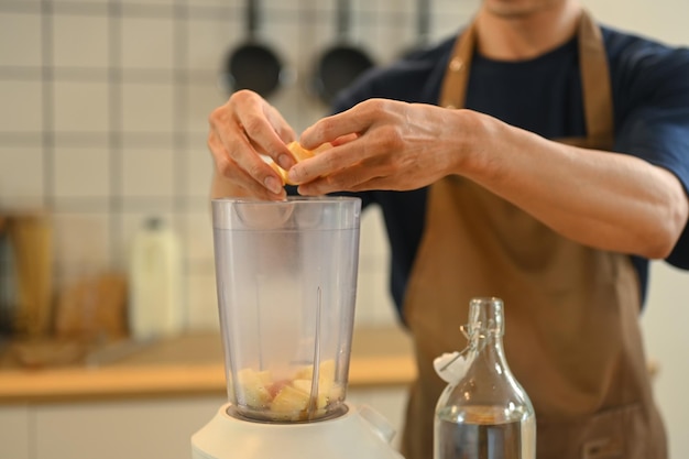 Fotografia recortada de um homem adulto fazendo um smoothie saudável no balcão da cozinha