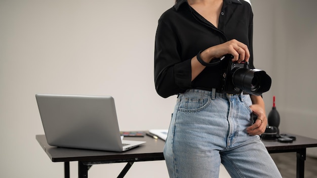 Foto una fotografía recortada de una fotógrafa está de pie en su estudio con una cámara dslr en la mano