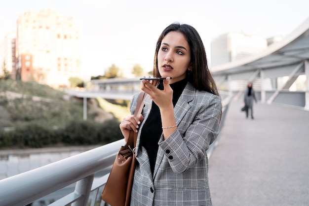 Foto fotografía de stock de una joven mujer de negocios escribiendo en su teléfono ella está caminando en la calle