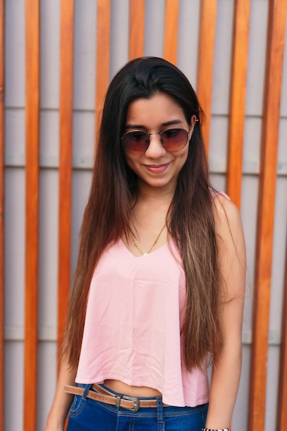 Fotografía de Stock de un retrato de una joven mujer de raza caucásica sonriendo. Lleva ropa informal y gafas de sol.