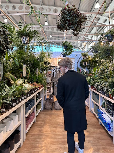 Foto fotografía trasera de un hombre caminando por pasillos con plantas en una tienda del centro de jardines