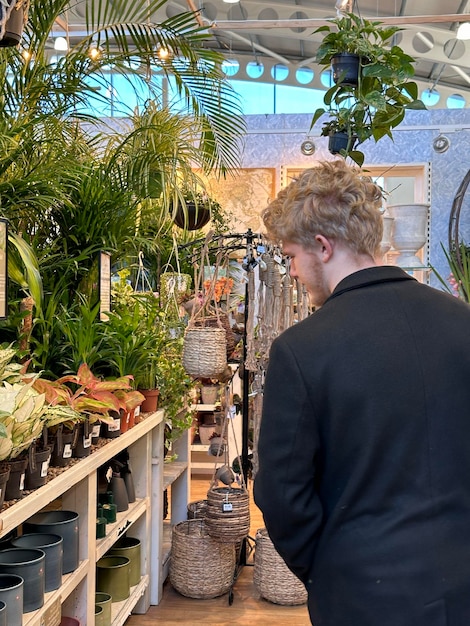 Foto fotografia vertical cortada de um cliente masculino comprando plantas em uma loja do centro de jardim