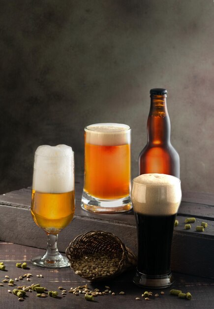 Fotografia vertical de diferentes copos com cerveja espumosa e uma garrafa de cerveja