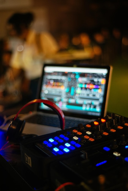 Fotografia vertical de foco seletivo de um mixador de som de disc jockey e uma tela de laptop em uma boate