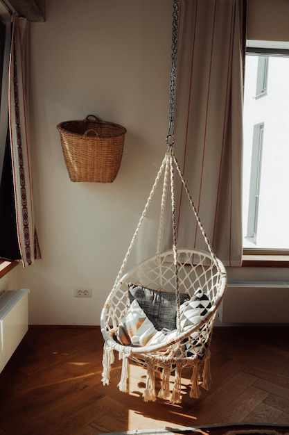 Fotografia vertical de uma cadeira pendurada de macrame em uma sala de estilo loft