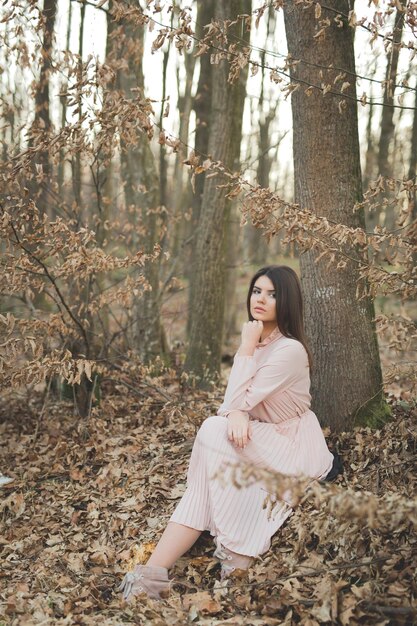 Fotografia vertical de uma mulher caucasiana vestindo um belo vestido rosa posando na floresta da Bósnia