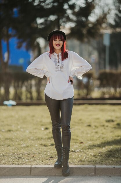 Fotografia vertical de uma mulher ruiva caucasiana de pé em um fundo desfocado