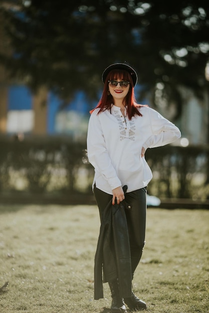 Fotografia vertical de uma mulher ruiva caucasiana de pé em um fundo desfocado