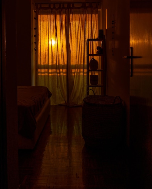 Fotografia vertical de uma sala aconchegante com um design retro e janelas fechadas na hora do pôr do sol