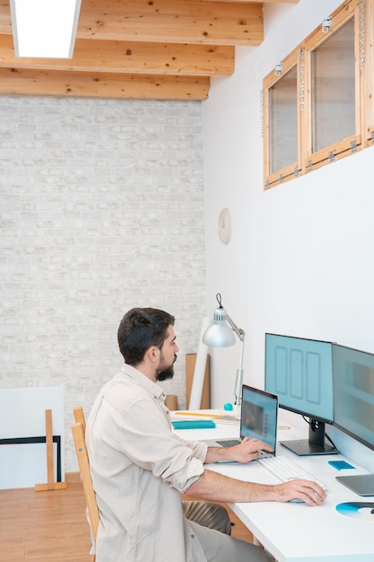 Fotografía vertical de un joven empresario trabajando en su computadora en una oficina de espacio de trabajo moderno en casa