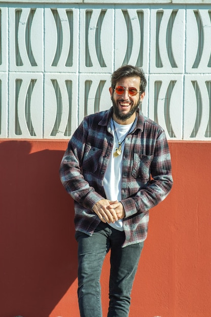 Fotografía vertical de un joven español feliz con una camisa a cuadros en el fondo de la pared