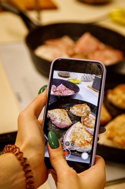 Foto fotografiando comida en un teléfono móvil smartphone tomando fotos del pollo en una sartén