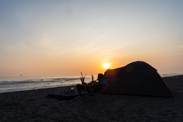 Fotografie eines roten Campingzeltes am Strand bei Sonnenuntergang von Yuri Ugarte Cespedes