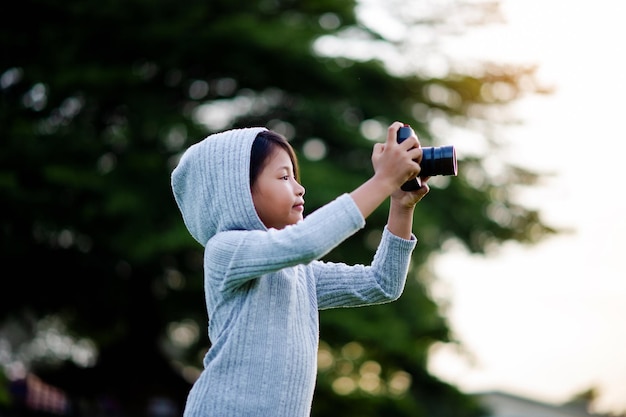 Fotografieren Sie mit einer spiegellosen Kamera. Kleines Mädchen übt wenig Naturfotografie