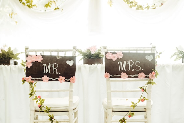 Fotografieren Sie mit zwei Stühlen voller Ornamente und Blumen mit einem Brief, der Mr. und Mrs. Concept Weddings and Heiratsfreiheit und Liebeskopienraumhintergrund sagt