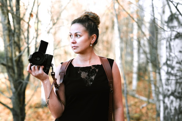 Fotografin in einem schwarzen langen Kleid mit Entladen auf zwei Kameras mit einer SLR- und Filmkamera