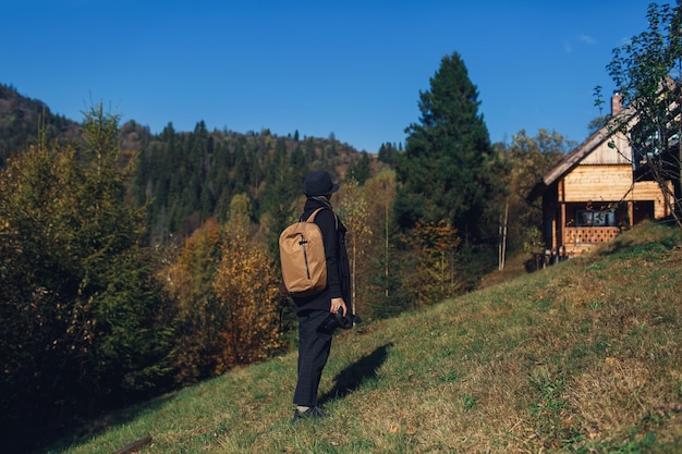 Fotografin mit Rucksack steht am Hang und sieht im Herbst die Natur in den Bergen.