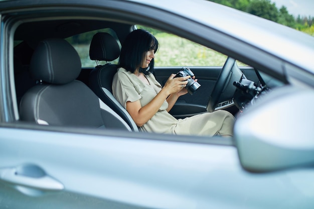 Fotografin sitzt im Auto und schaut auf das Foto auf der Kamera, Reisefrau macht Foto, Platz für Text