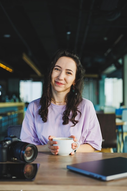 Foto fotografin, studentin mit kaffee, laptop benutzt, arbeitet mit fotografie in einem coworking-space, junge freelancer arbeitet aus der ferne mit webdesign