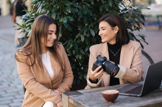 Fotografin zeigt ihren Kunden Fotos und sie wählen Fotos in der Kamera. Glückliche Frauen lächeln und