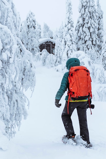 Fotografin zu Fuß zu einer Hütte im verschneiten Wald