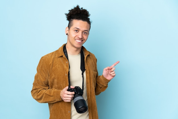 Fotografmann über lokalisiertem blauem Hintergrund, der Finger zur Seite zeigt