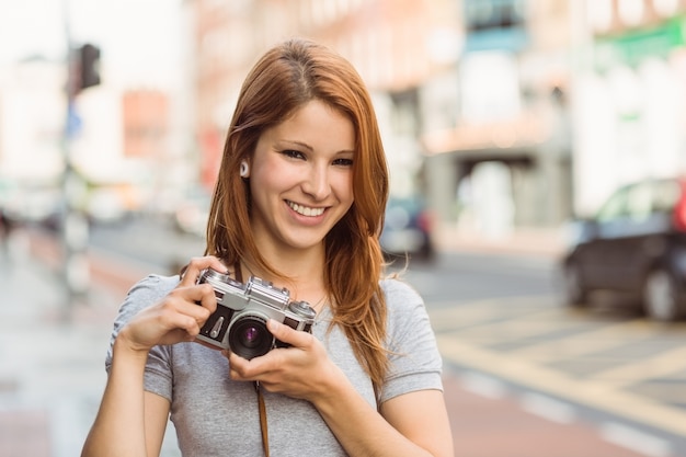 Fotógrafo alegre de pie afuera sonriendo a la cámara