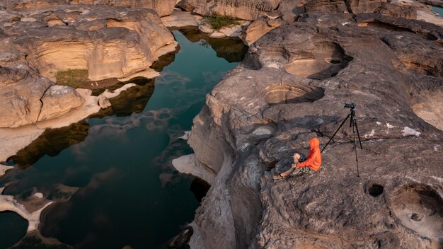 Fotógrafo de archivo y cámara sentado rock stone en sam phun boke grand canyon ubon Ratchathani Tailandia