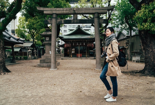 fotógrafo asiático caminhando visitando a famosa atração tenmangu em osaka japão. lugar histórico tranquilo cercado por árvores. torii de pedra e lanternas de toro no xintoísmo.