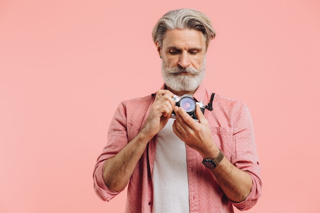 Fotógrafo barbudo de mediana edad con una cámara en rosa.