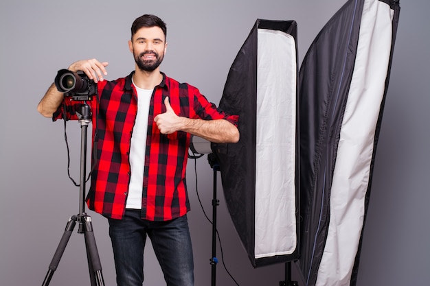 Fotógrafo bonito com câmera no estúdio fotográfico gesticulando