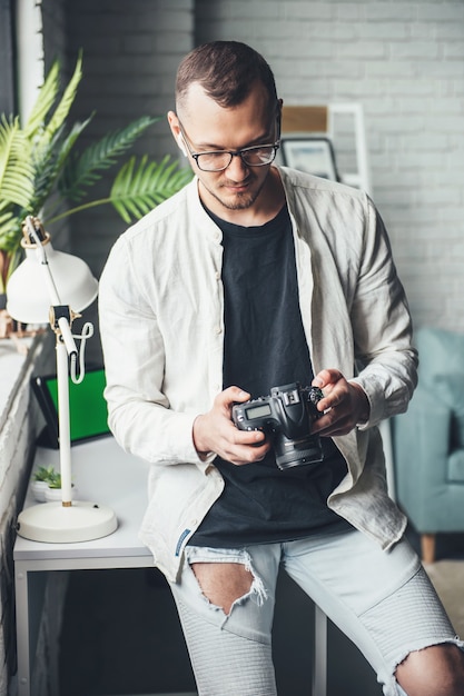 Fotógrafo calvo está usando una cámara de fotos en casa con gafas mientras mira la pantalla