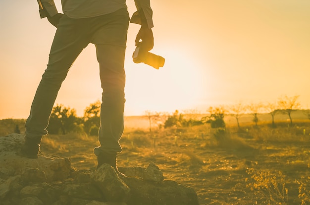 Foto fotógrafo con cámara en mano disfrutando del atardecer