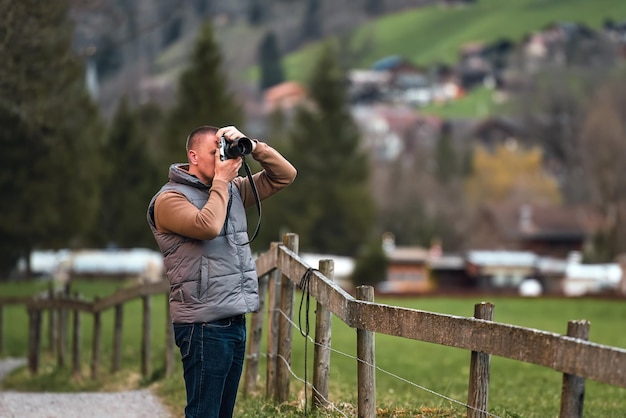 Fotógrafo con una cámara tomando una fotografía de las montañas nevadas contra el cielo azul en el concepto Alps Wanderlust