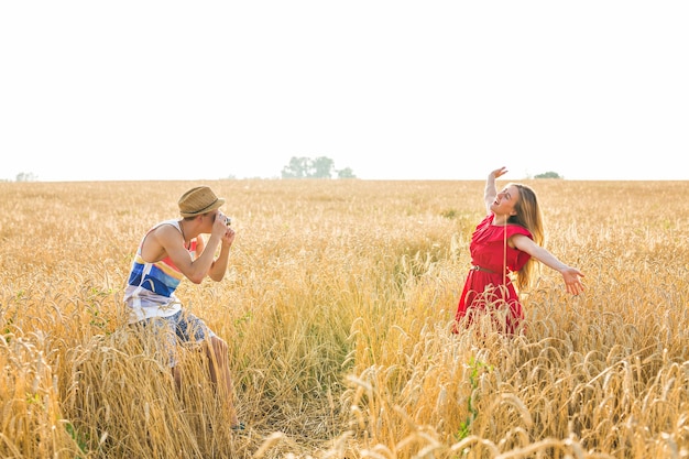 Fotógrafo con cámara tomando fotografías de mujer joven y bella en el campo.