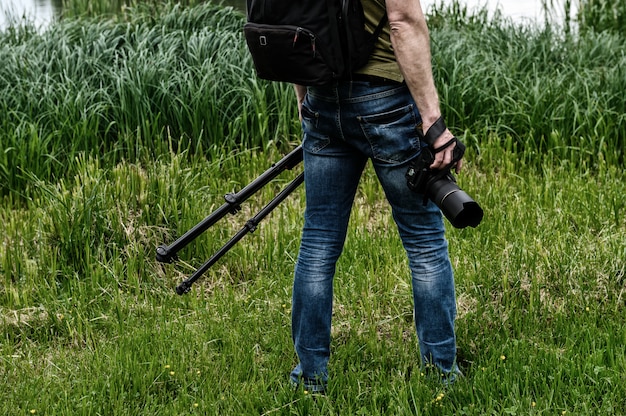 Foto fotógrafo con cámara y trípode en el fondo de un lago de la ciudad.